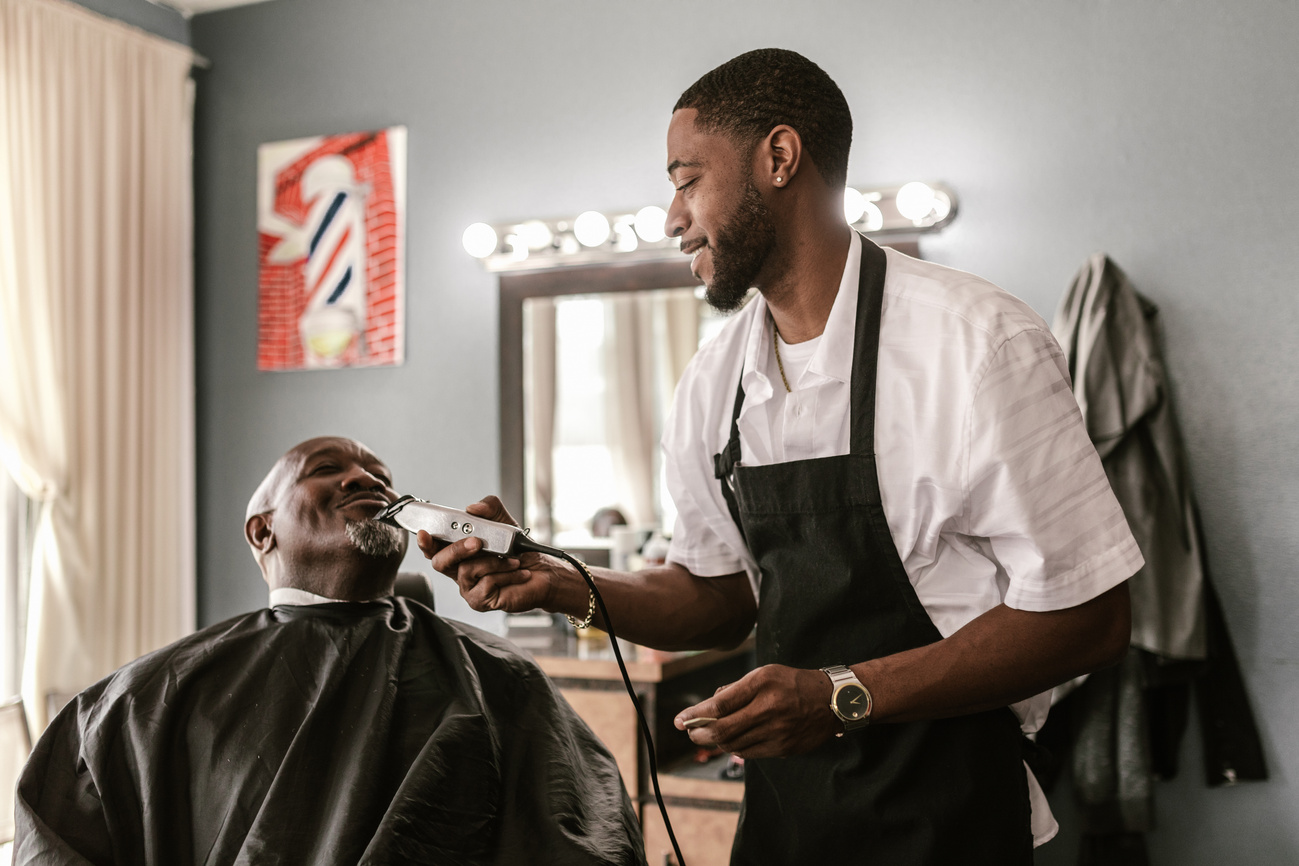 Man in White Shirt Cutting Hair of Man in Black Apron